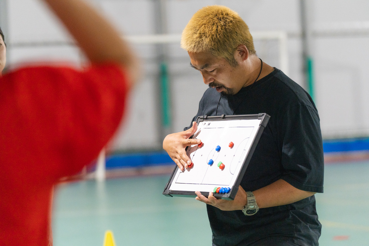 山岸輝久監督と作戦ボードを確認する選手
